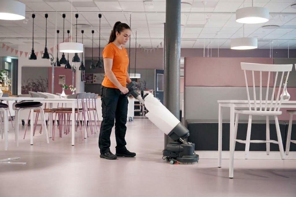 Kvillestäds lokalvårdare kör golvskurmaskin vid akutstädning i kontorsmiljö i Göteborg